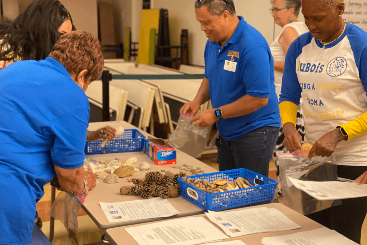 Several people standing around a table with craft supplies and papers.