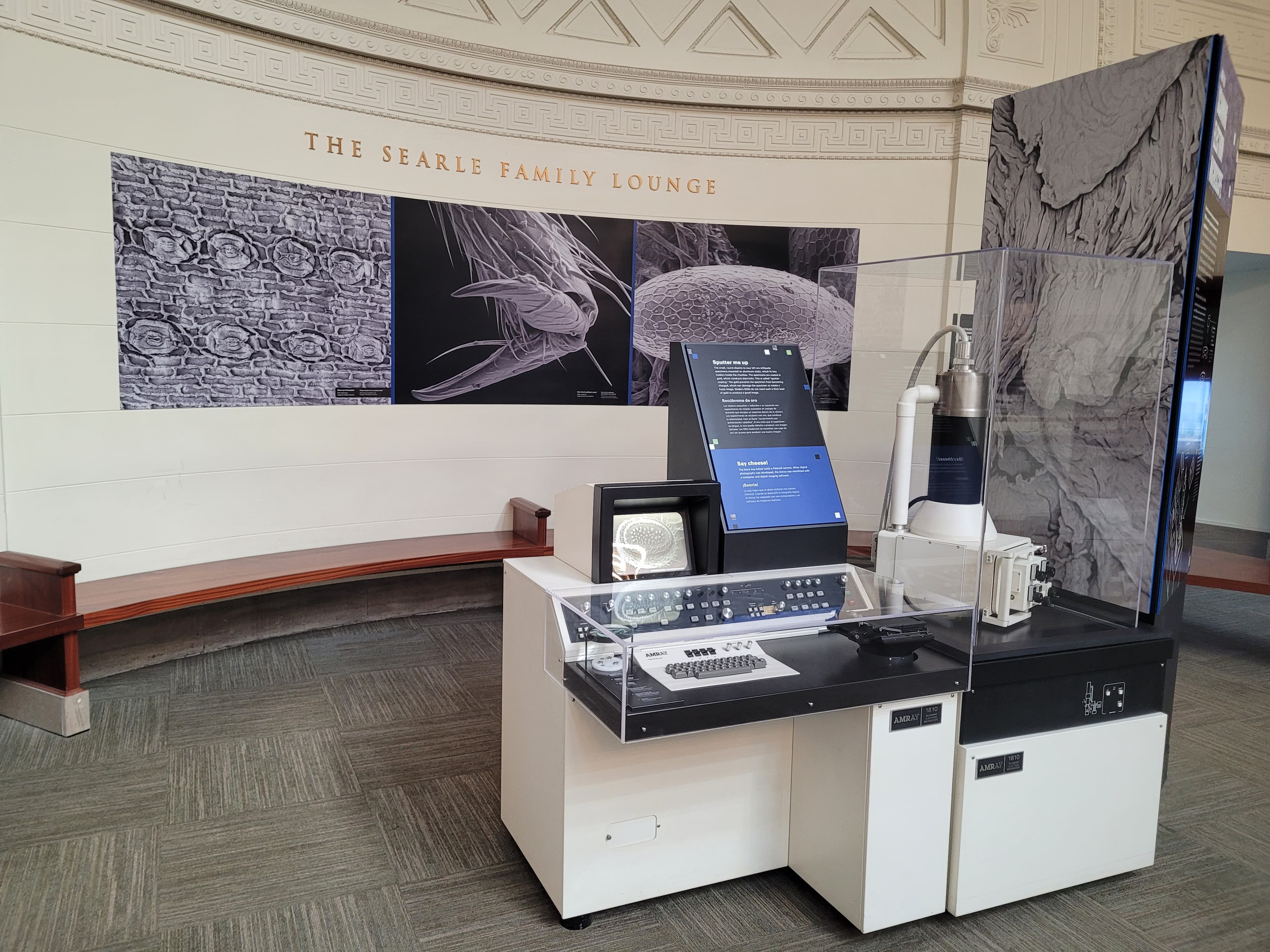 A scanning electron microscope, with images taken with it displayed on the wall behind.