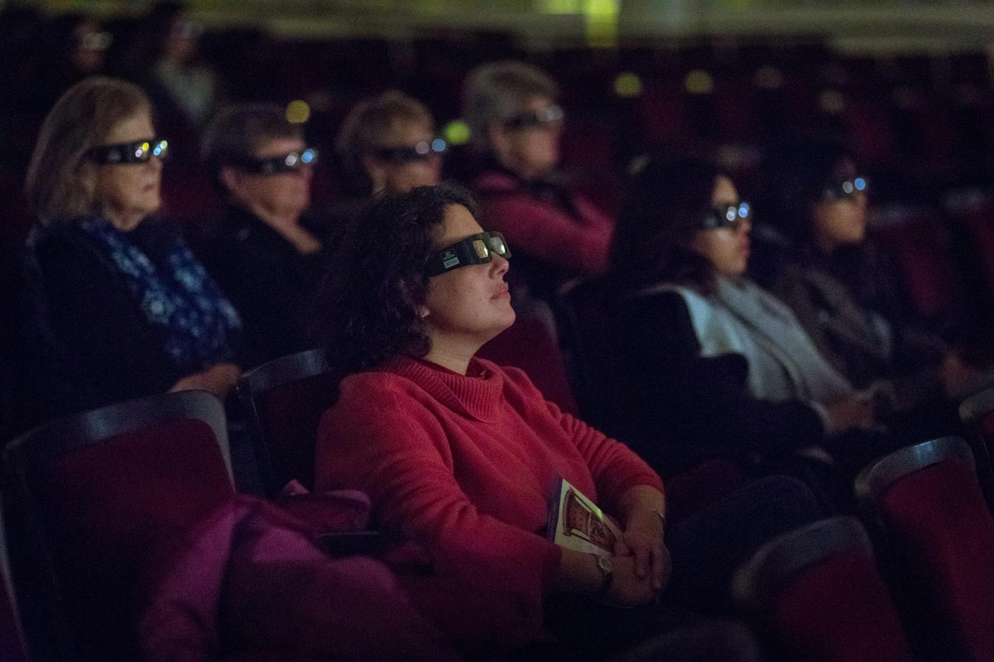 Visitors wearing 3D glasses, looking towards a movie screen that is not visible in the frame.