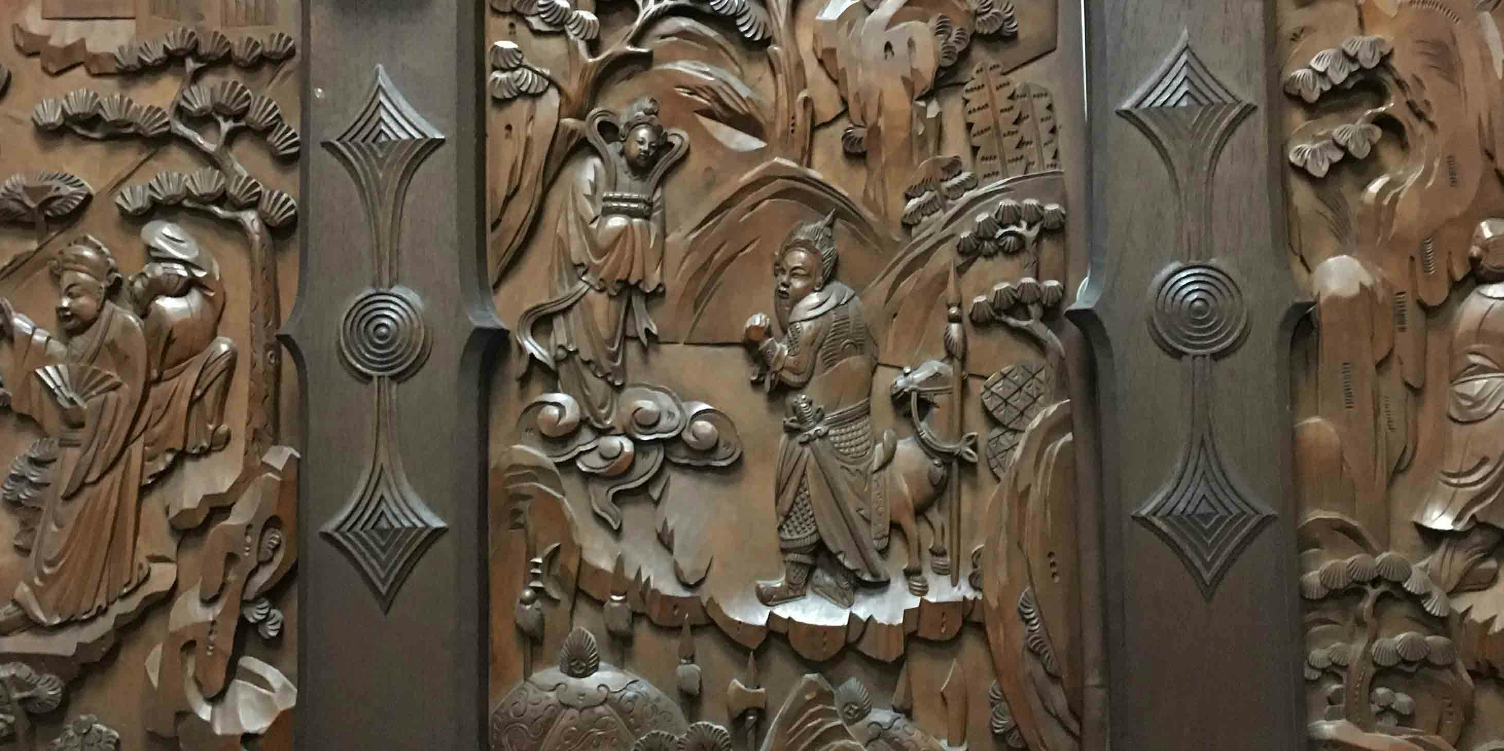 Detail of intricate wood carving, with a man with a sword and a horse depicted