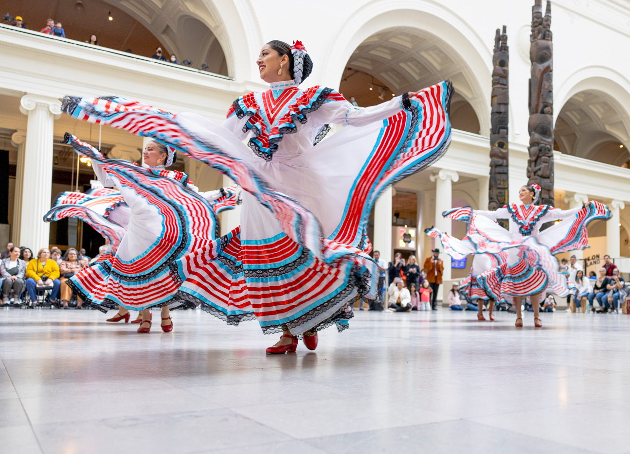 Women wearing traditional clothing dance in the museum's main hall