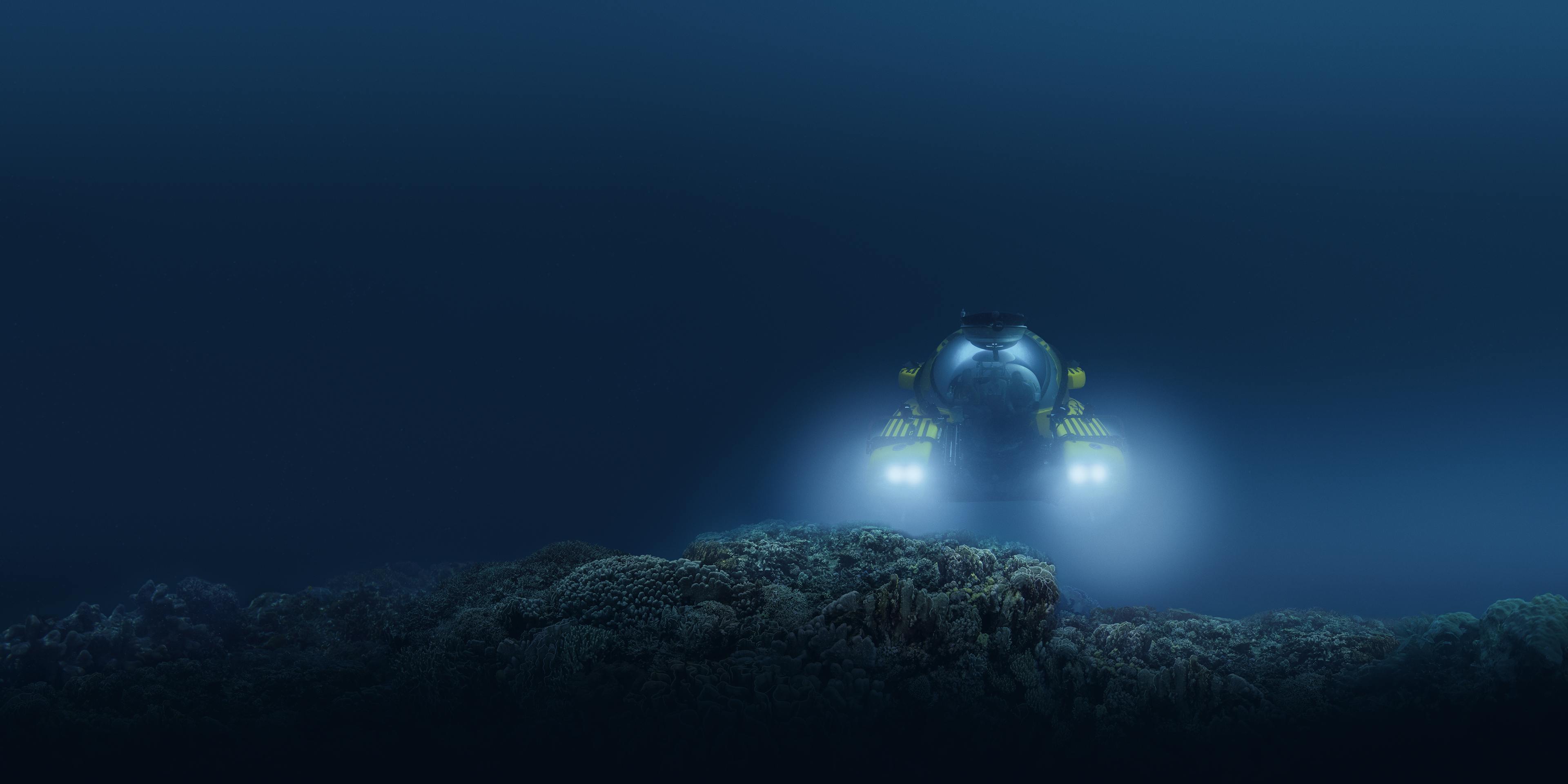 An underwater image of a submersible with its headlights illuminating a rock formation.